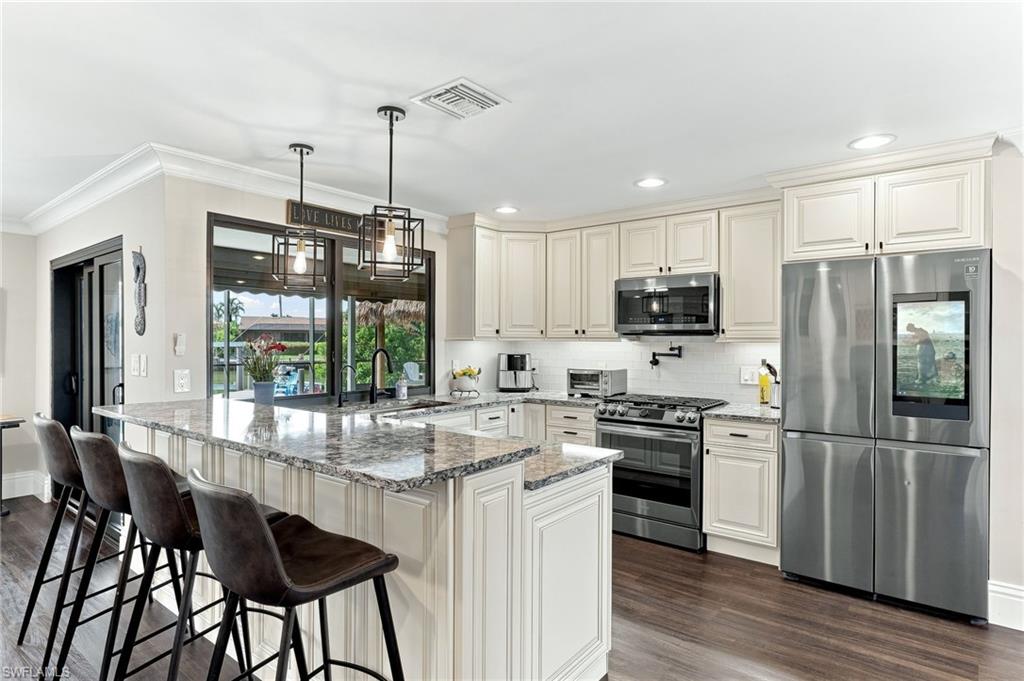 Kitchen featuring light-toned cabinetry, stainless steel appliances, granite countertops, and wood-finish flooring