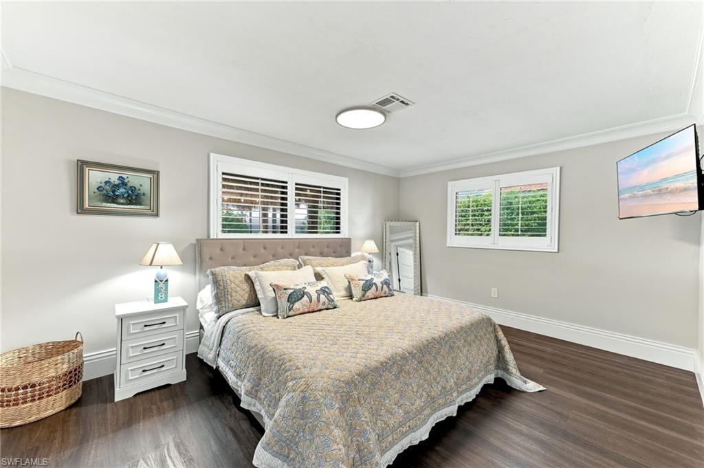 Wood-finish flooring, crown molding, plantation shutters, and a ceiling-mounted light fixture