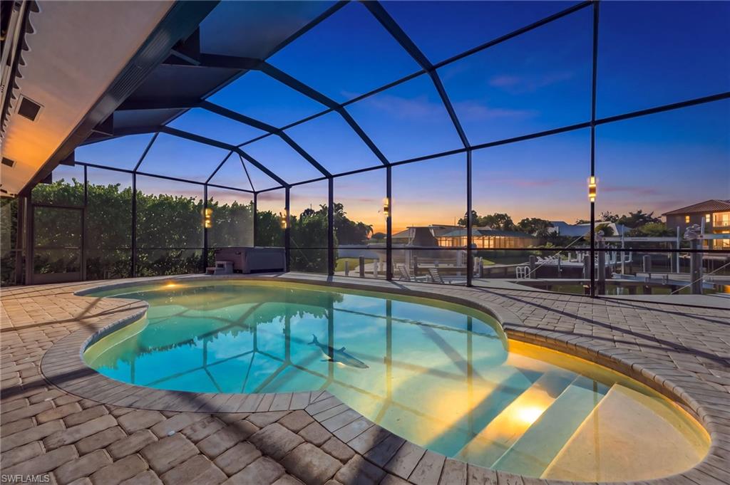 Screened enclosure encompassing a freeform pool, integrated spa, and paver decking