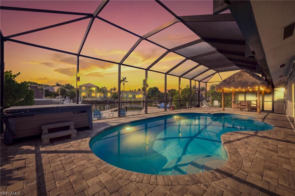 Resort-style pool with illuminated water features and curved design, sheltered beneath a polycarbonate enclosure with metal framing
