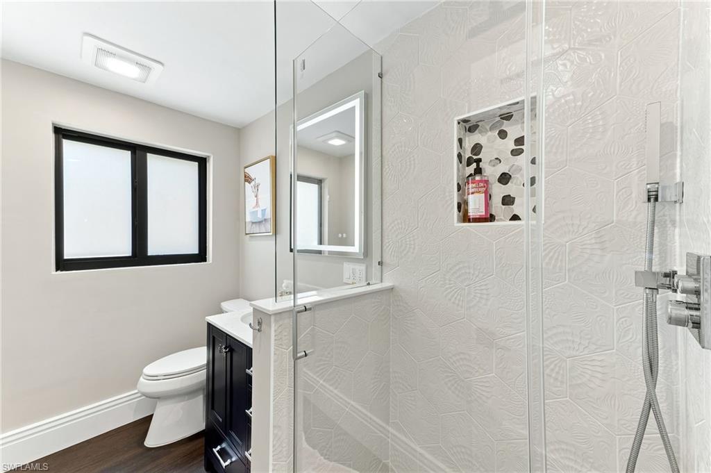 Walk-in shower with clear glass enclosure, textured tile surround, and an integrated tiled niche