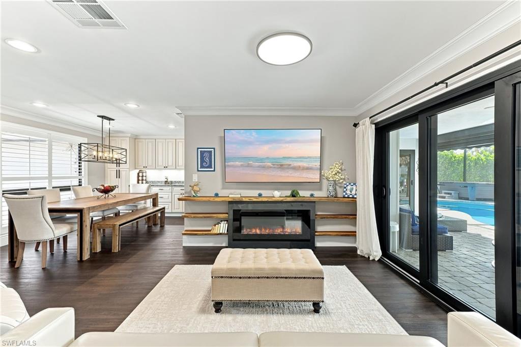 Dark wood-finish flooring throughout, crown molding, and an electric fireplace with built-in shelving