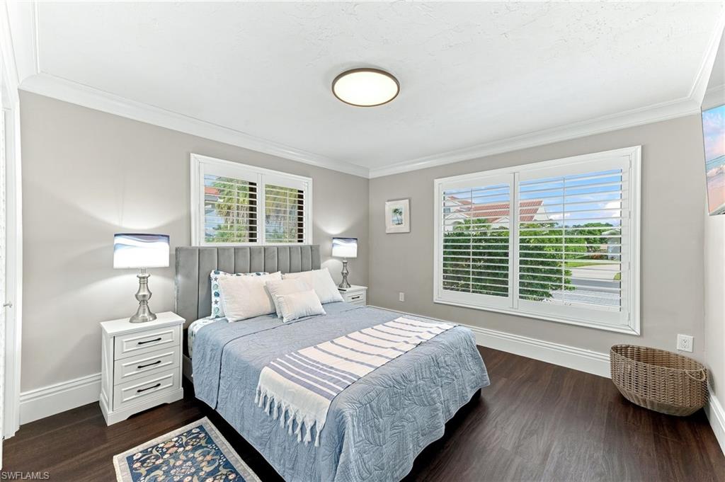 Wood-finish flooring, crown molding, and two windows with plantation shutters
