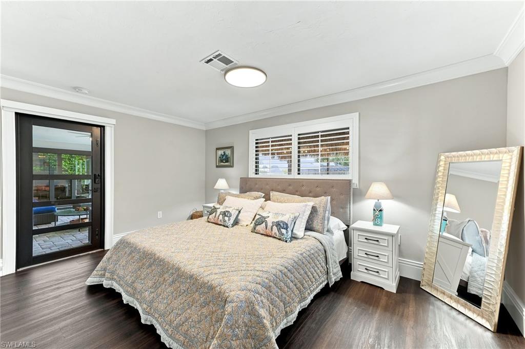 Wood-finish flooring, crown molding, white window shutters, and a sliding glass door providing outdoor access