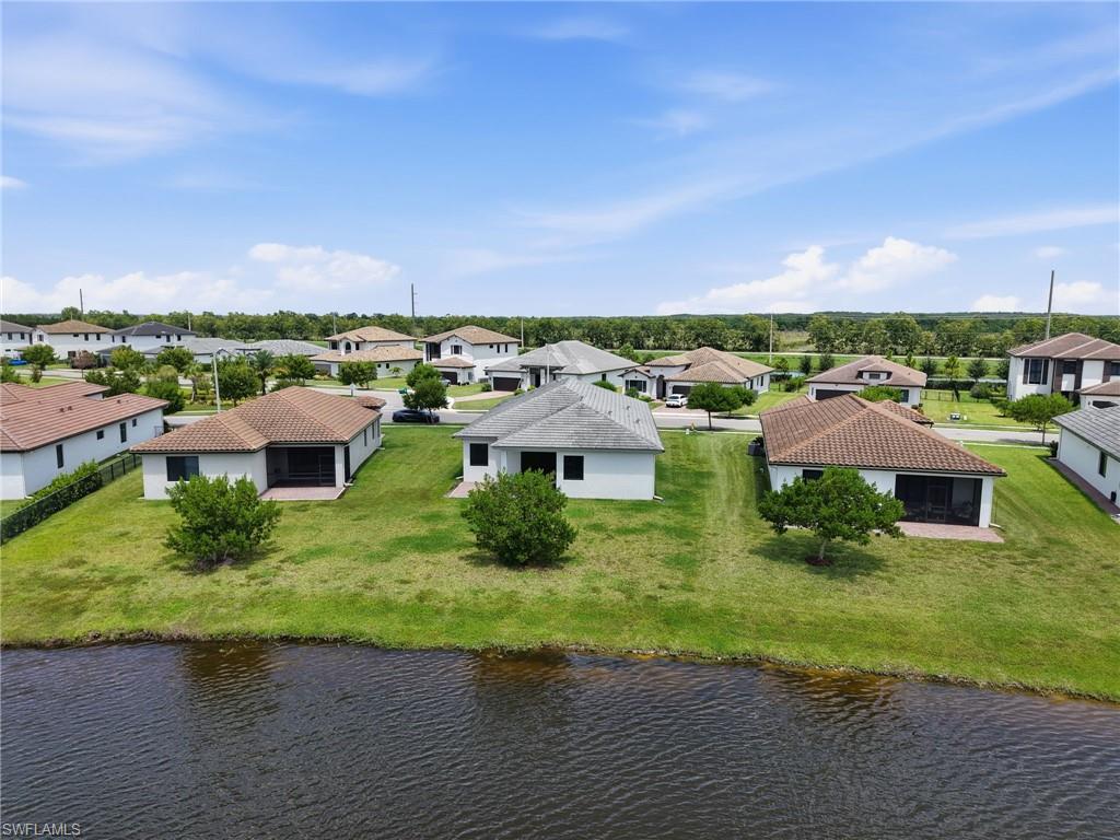Waterfront property with a screened lanai, mature landscaping, and a tile roof