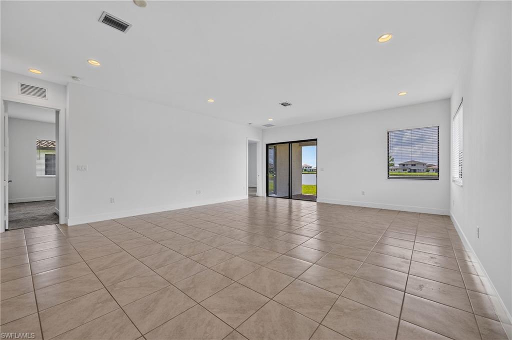 Spacious room with neutral-toned tile flooring, recessed ceiling lights, and white wall finishes