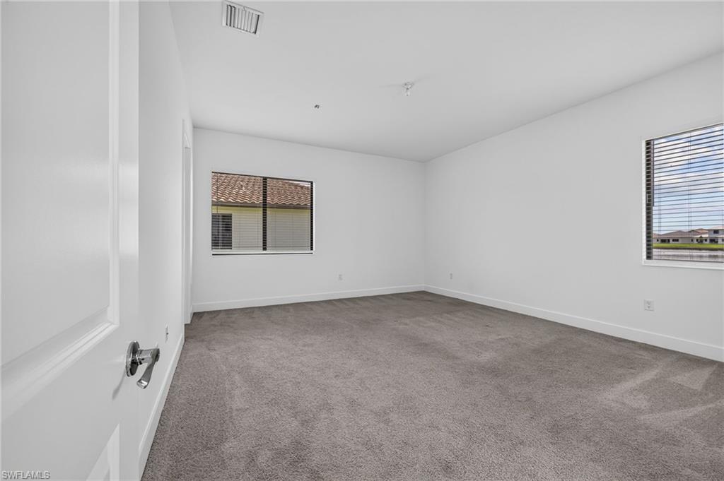 Neutral wall paint, carpet flooring, and two windows with horizontal blinds