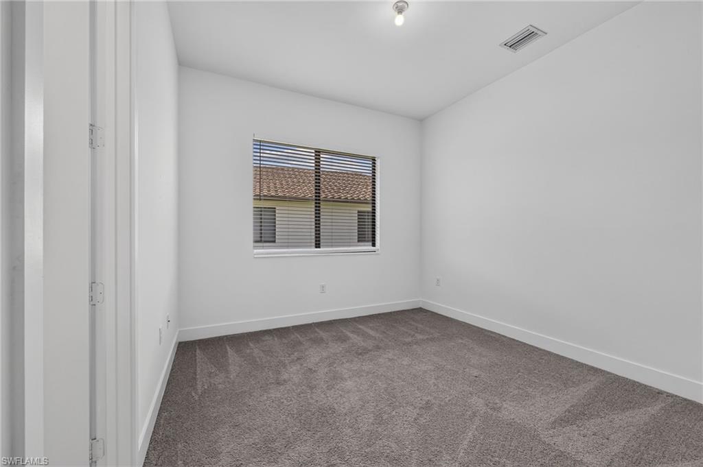 Neutral wall finishes, recessed window with horizontal blinds, and gray carpeting