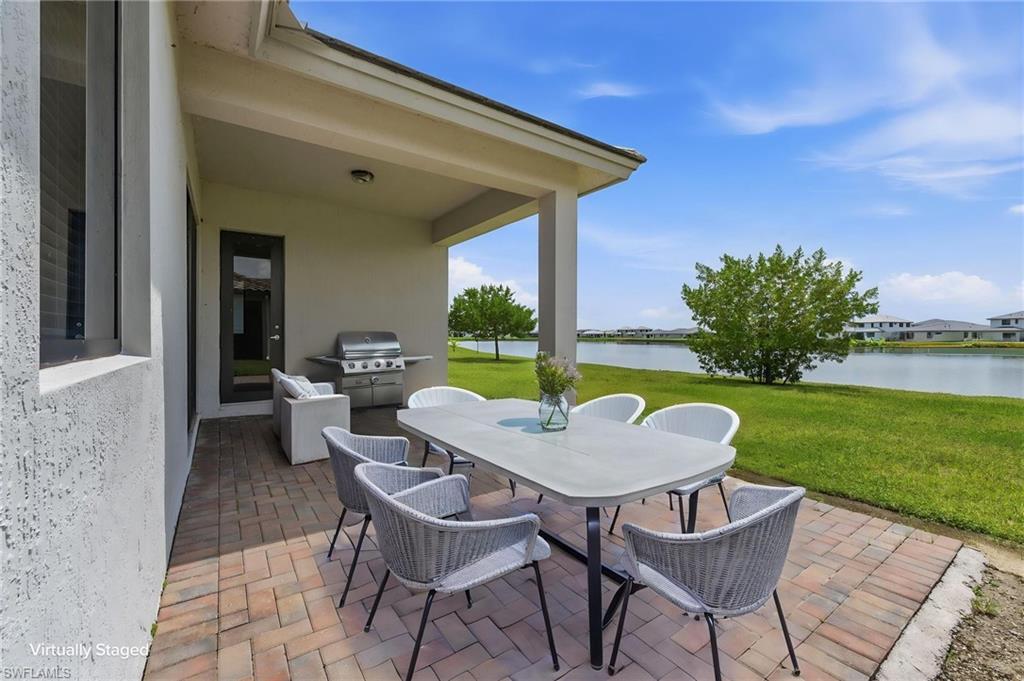 Covered patio with brick paver flooring and a water backdrop