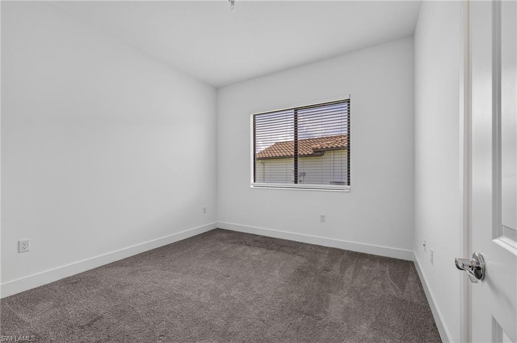 Recessed window with horizontal blinds, neutral wall paint, and gray carpet flooring