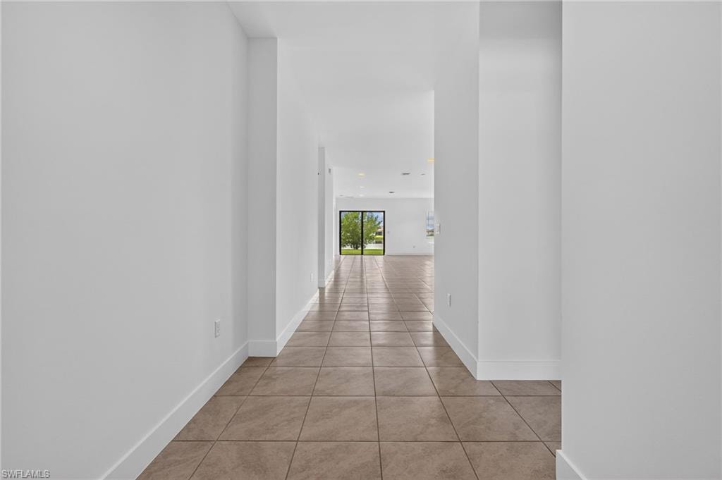 Hallway with tile flooring, white walls, and a recessed ceiling