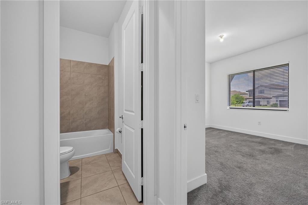 Bathroom with ceramic tile flooring and a bathtub with tiled surround