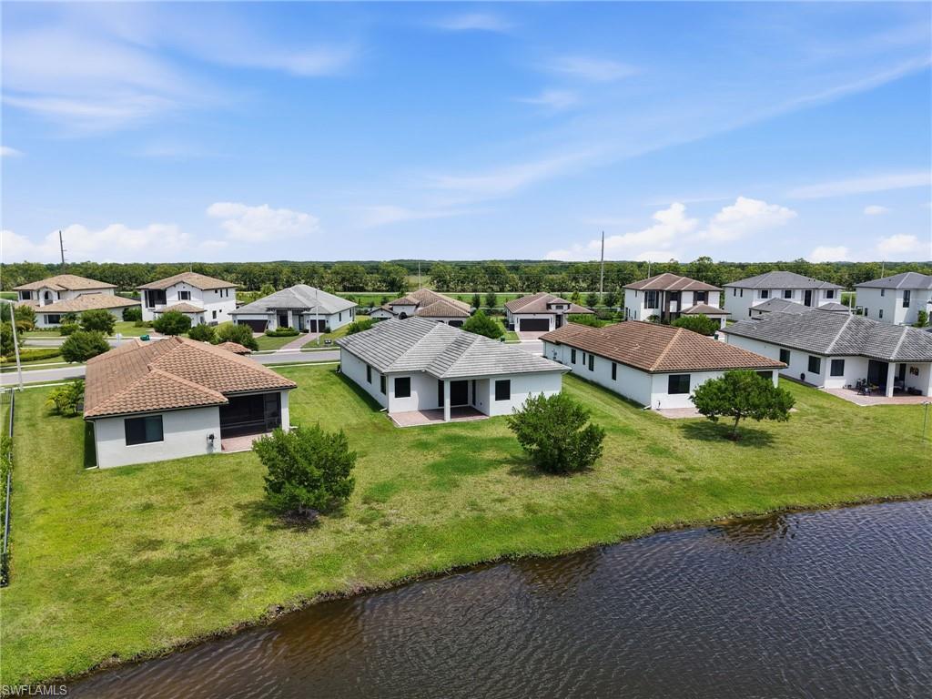 Waterfront property featuring a manicured lawn, covered patio, and tile roof