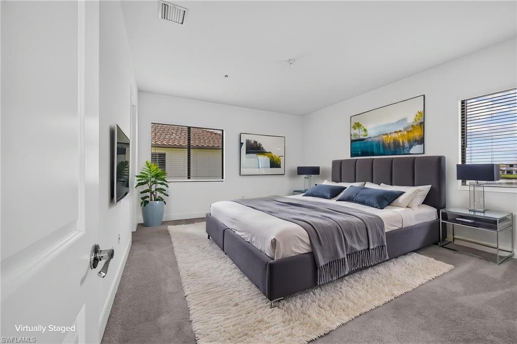 Wall-mounted television, windows with blinds, recessed lighting, and carpeted flooring