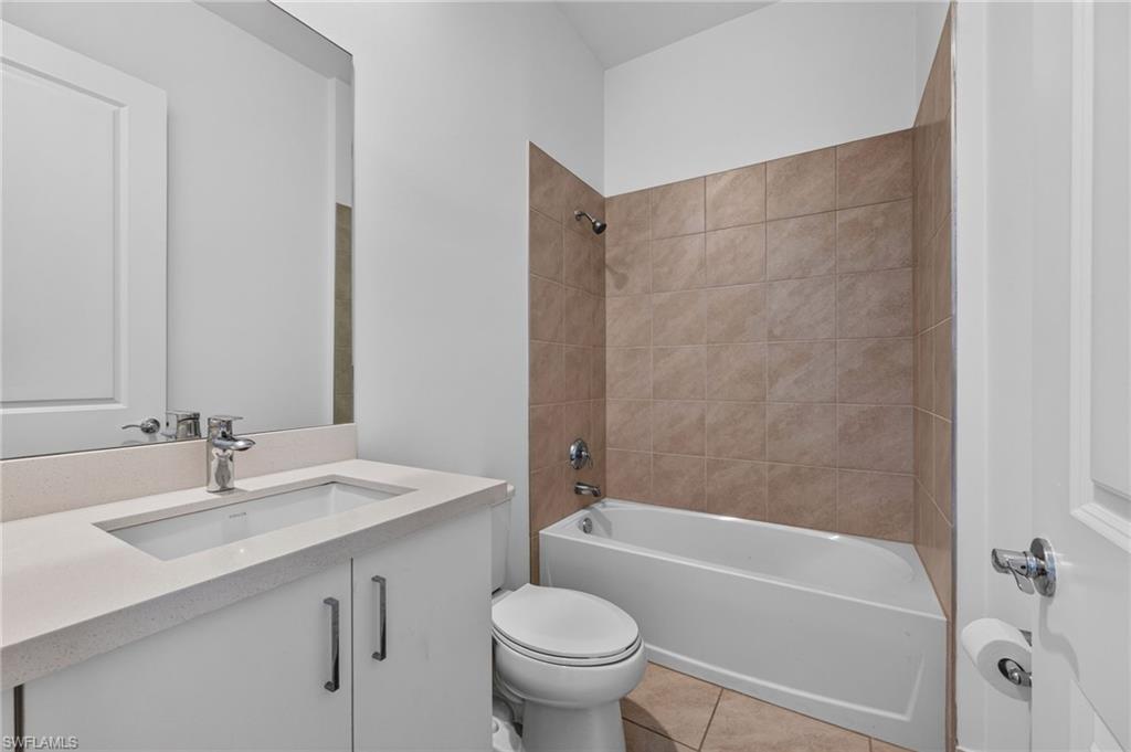 White vanity with a single basin sink, light-toned countertop, and chrome faucet