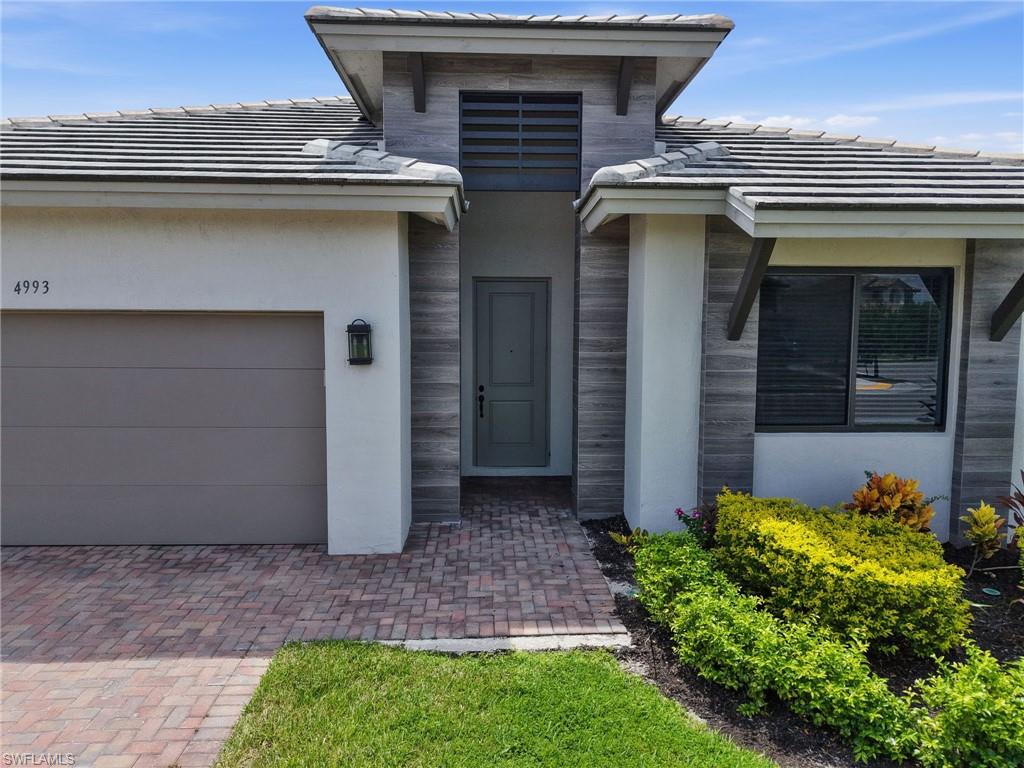 Modern architectural exterior with a tiled roof, wood-look accents, and an integrated garage