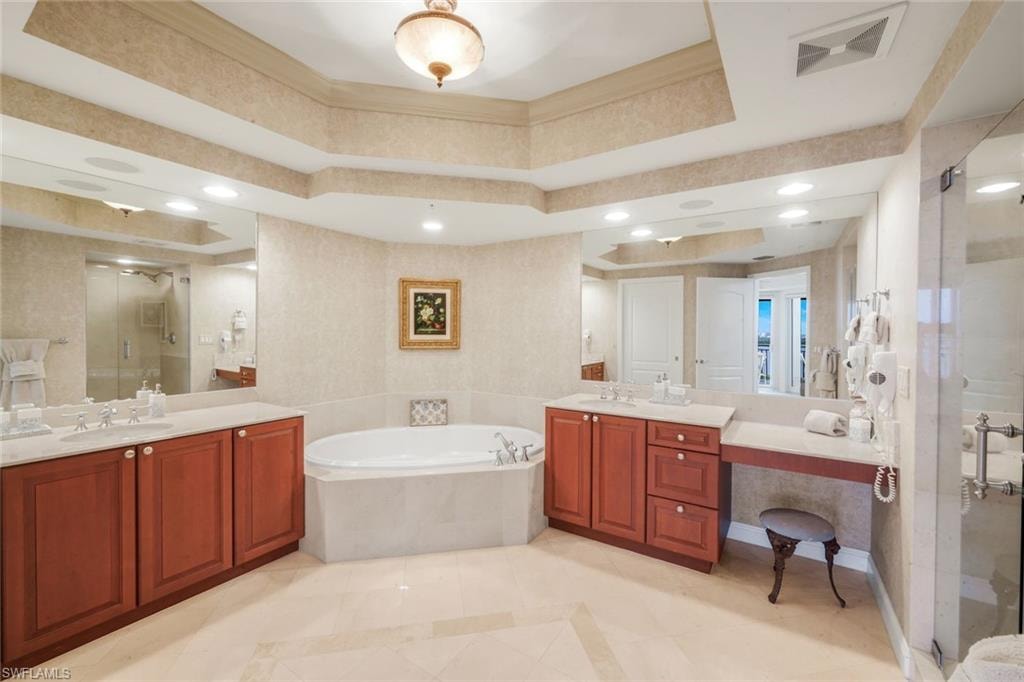 Primary bathroom with dual sinks, raised vanities, spacious shower and soaking tub.