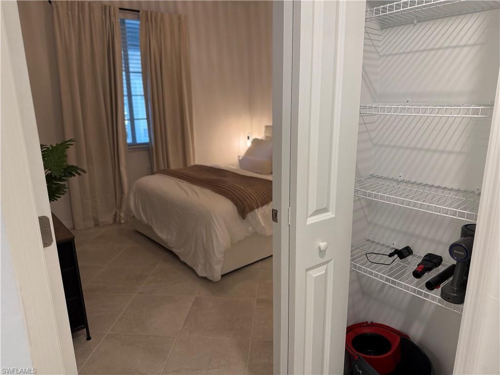 Recessed window with blinds, full-height drapery, tile flooring, and integrated closet shelving