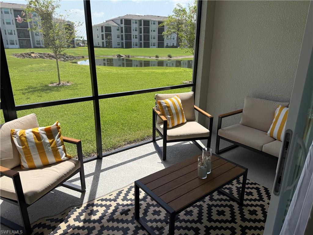 Screened-in outdoor space featuring textured wall surfaces, a light-toned flooring, and direct access to an expansive green area with a pond