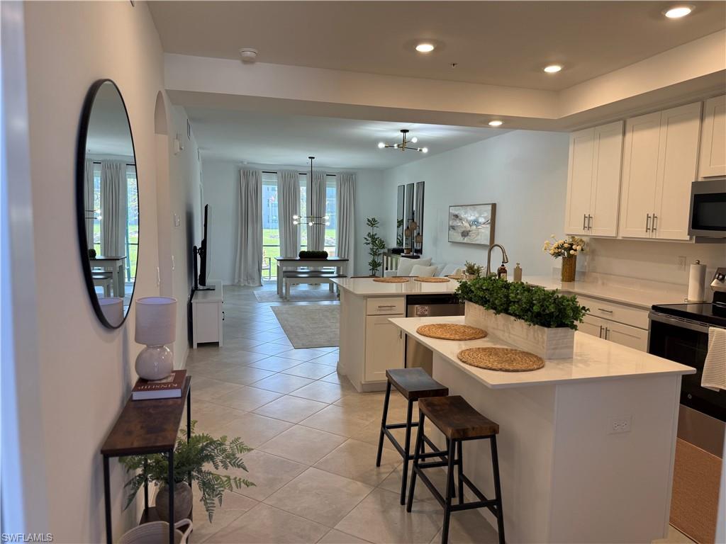 Open-concept kitchen with white shaker cabinetry, stainless steel appliances, and a central island with countertop seating