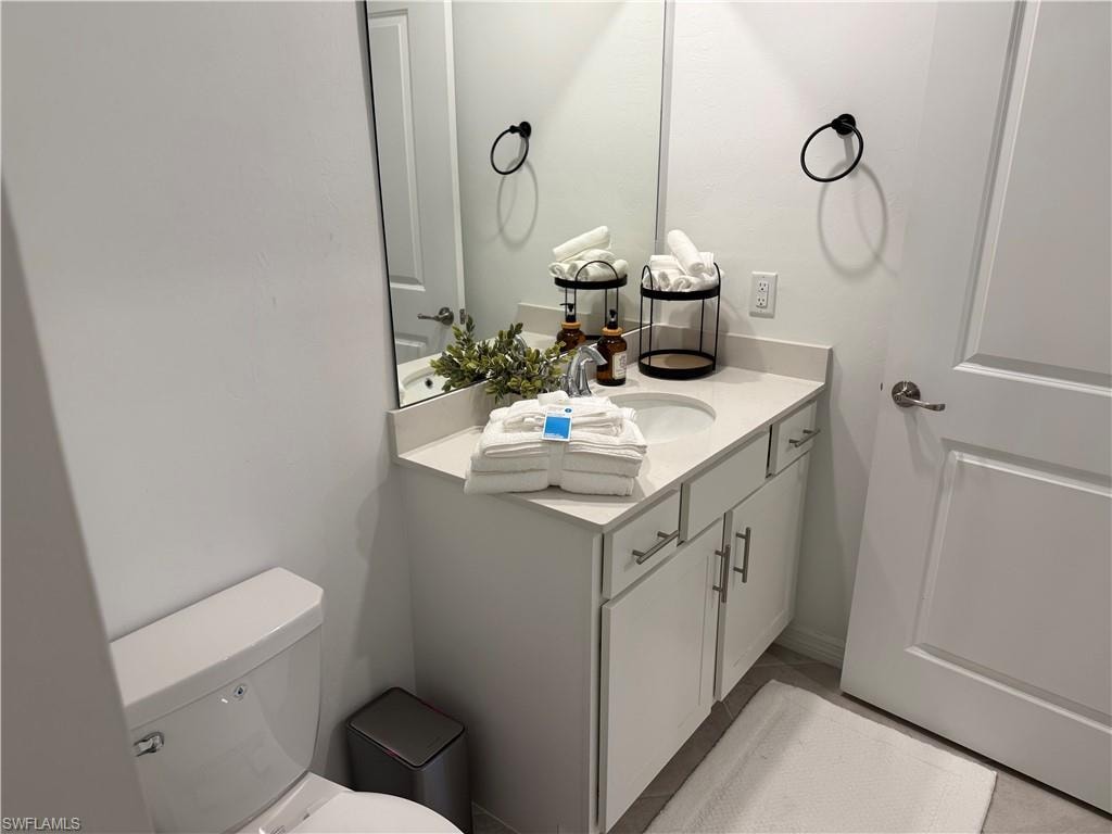 White vanity with a single basin sink, light-toned countertop, and undermount cabinetry with brushed nickel hardware