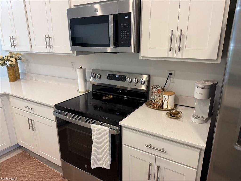 White cabinetry, light-toned countertops, stainless steel appliances, electric range, and an over-the-range microwave