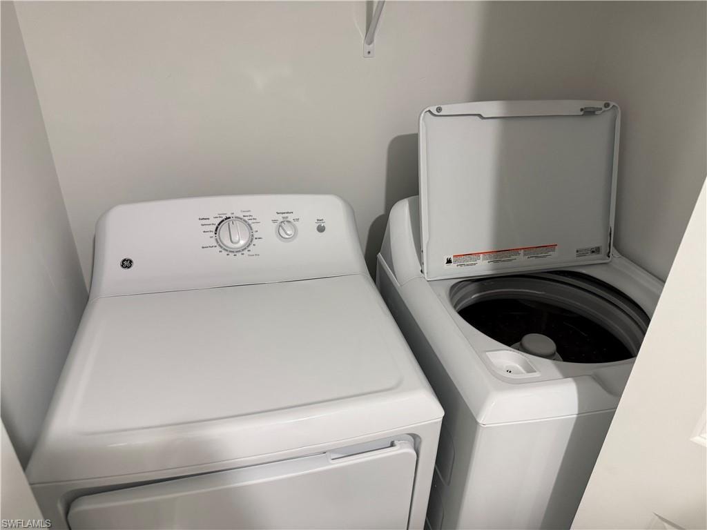 Dedicated laundry area with a white washing machine and dryer, featuring a built-in shelf