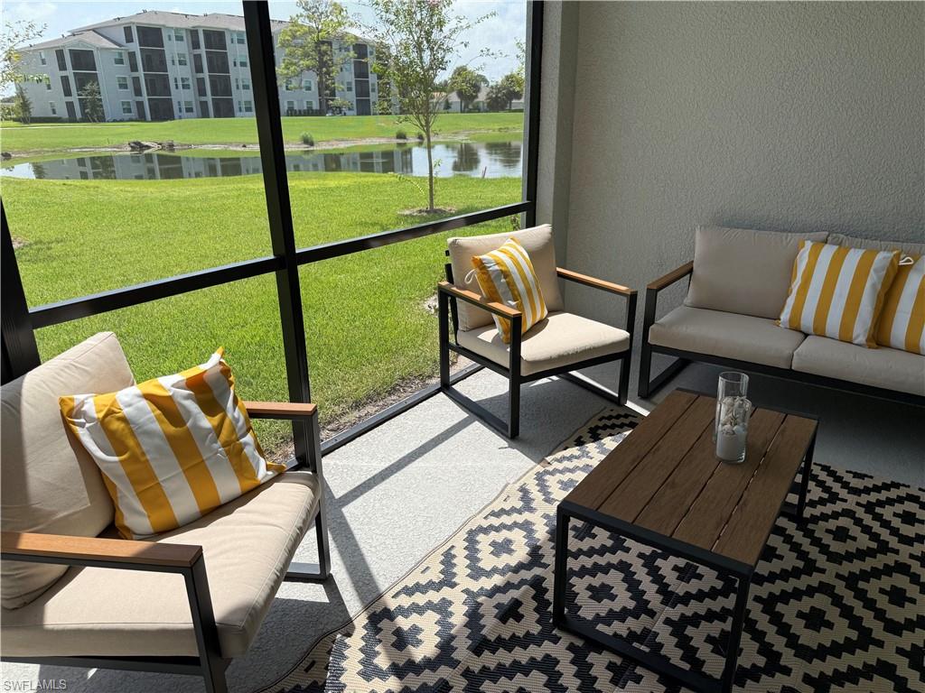 Screened lanai featuring a textured wall, a water body, and a green space