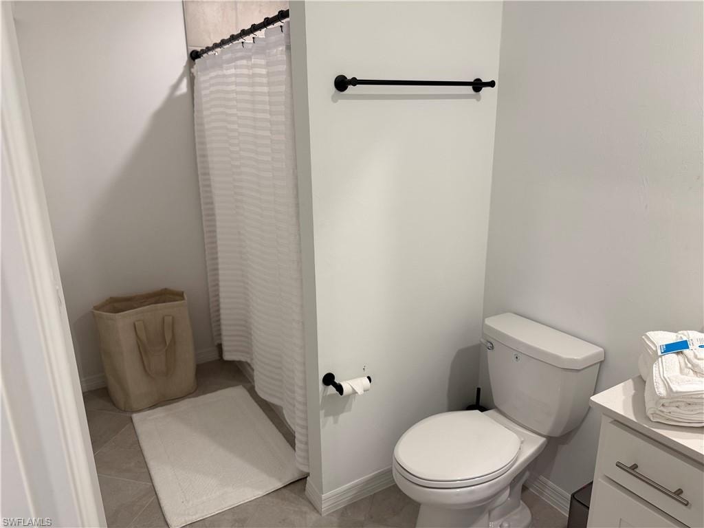 Shower with dark-finish curtain rod, wall-mounted toilet paper holder, and a towel bar