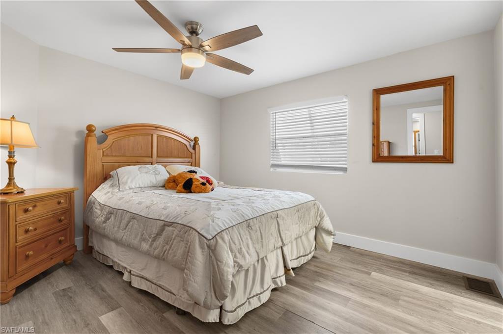 Comfortable guest bedroom with wide-plank flooring and neutral finishes.