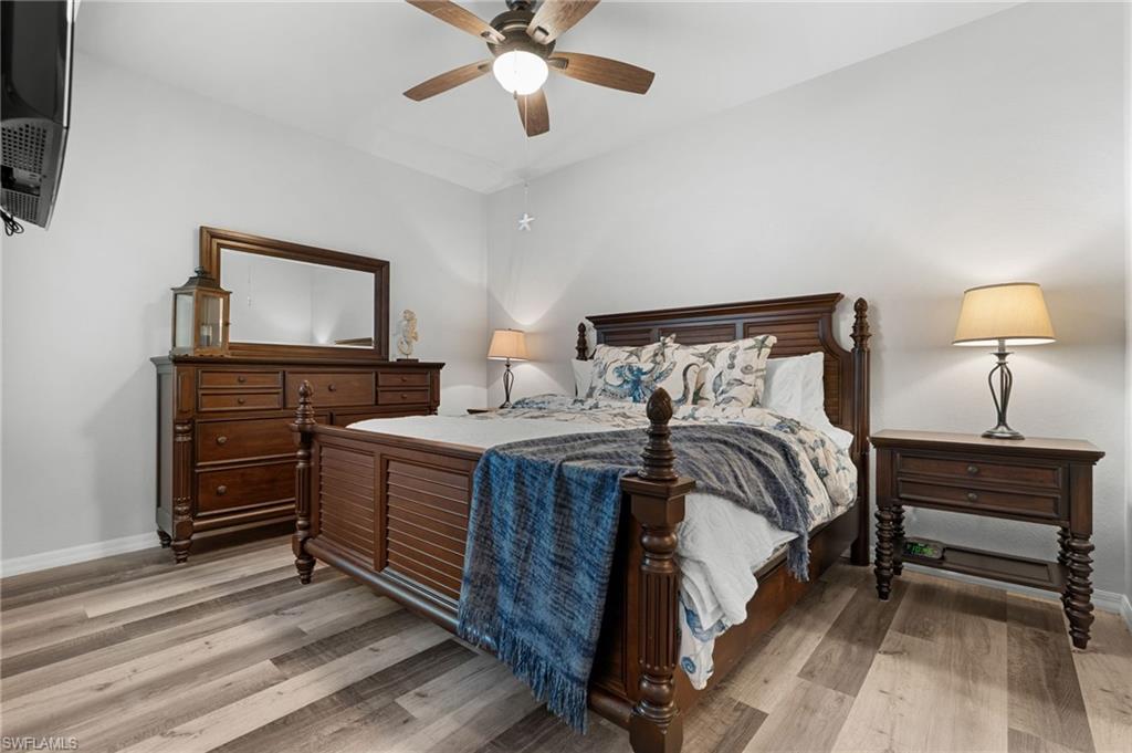 Master bedroom with wood-finish vinyl flooring, ceiling fan with integrated lighting