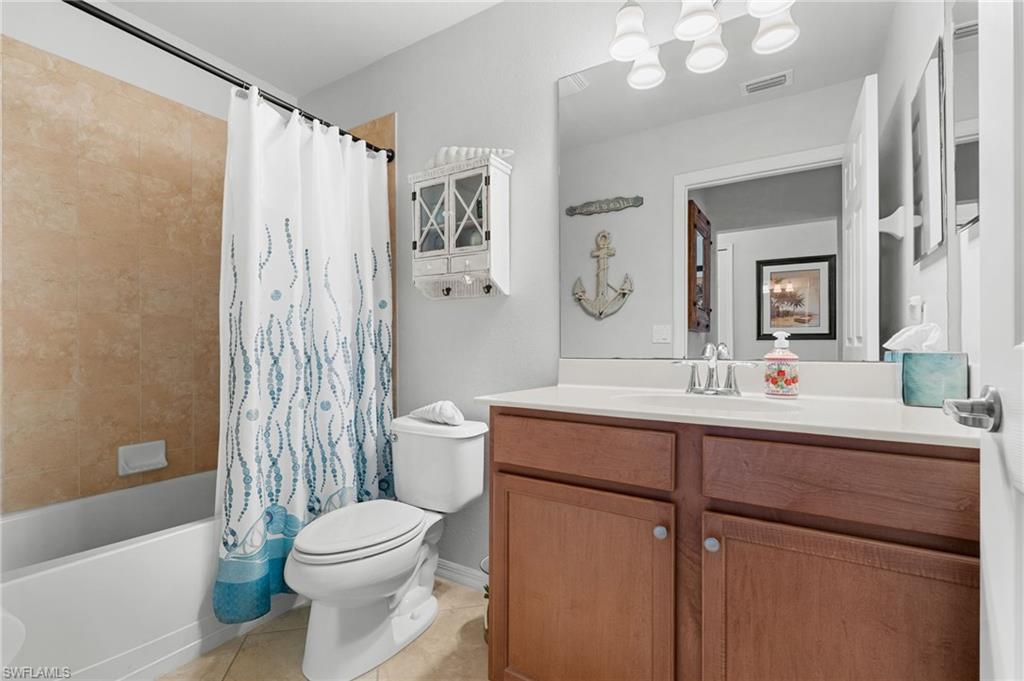 Bathroom featuring a single vanity with wood-finish cabinetry, a white countertop, and a large wall-mounted mirror