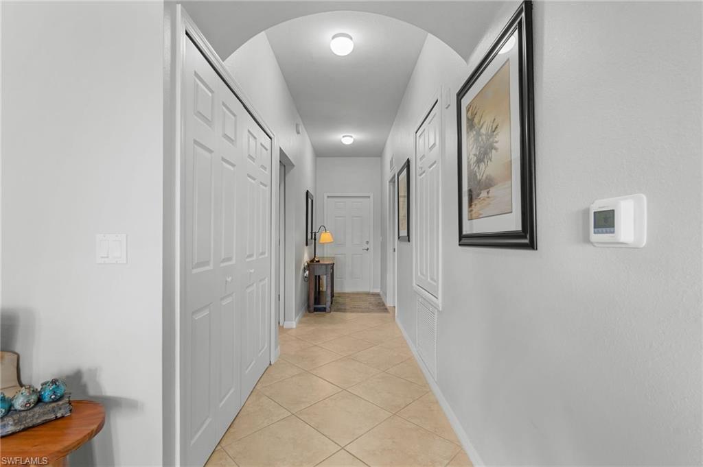 Arched hallway with recessed lighting and tiled flooring