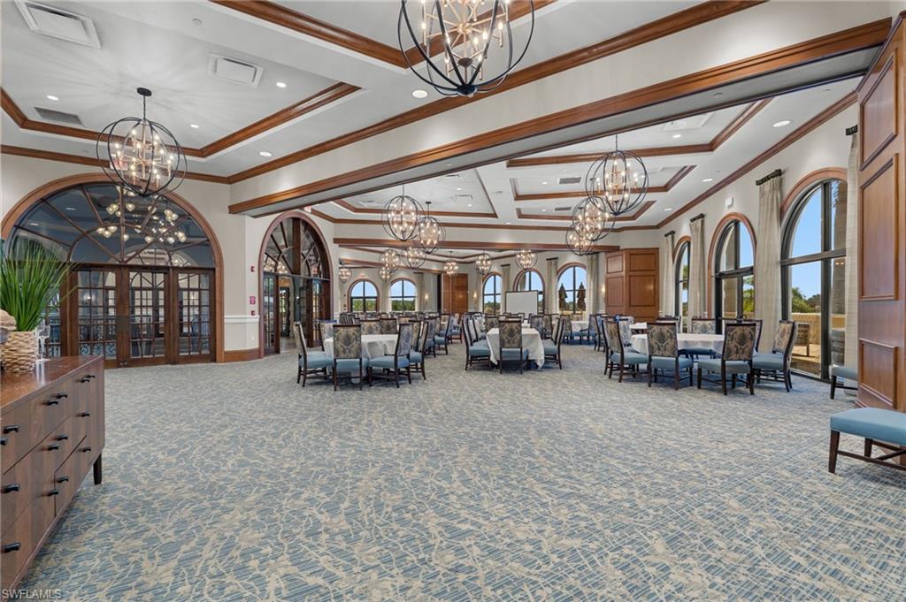 Expansive event space featuring arched windows, coffered ceilings with exposed wood beams, and multiple ornamental chandeliers