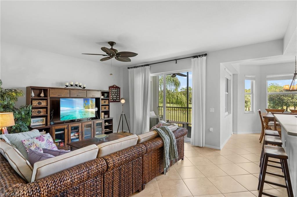 Travertine-style tile flooring, ceiling fan, and sliding glass doors to a screened lanai