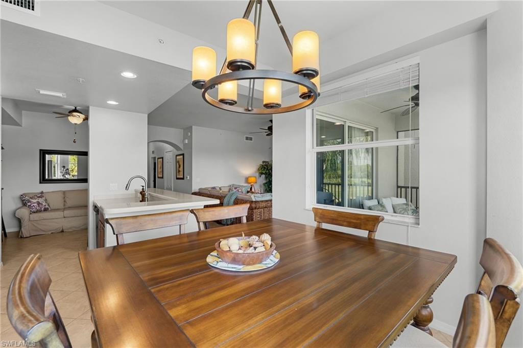 Spacious dining area with a multi-light chandelier, a breakfast bar with a sink, and an expansive window
