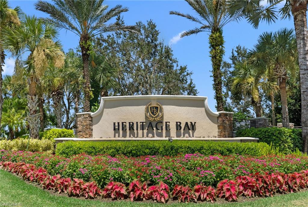 Monument sign with stone accents, lush landscaping, and mature palm trees