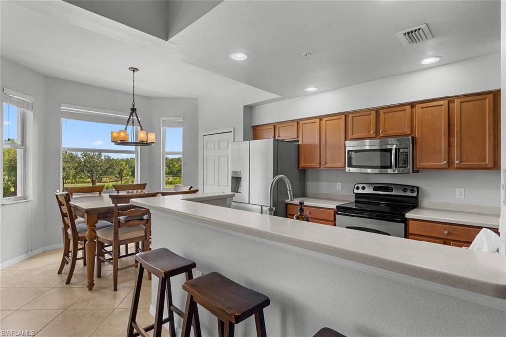 Kitchen featuring wood cabinetry, stainless steel appliances, a breakfast bar, and tile flooring