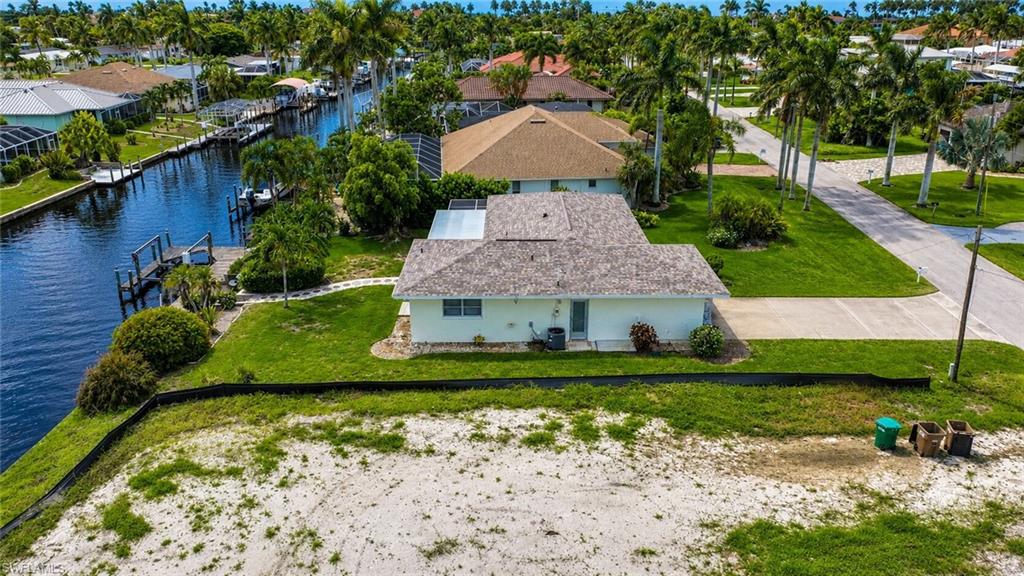 Waterfront property with private dock, mature landscaping, and an expansive paved driveway