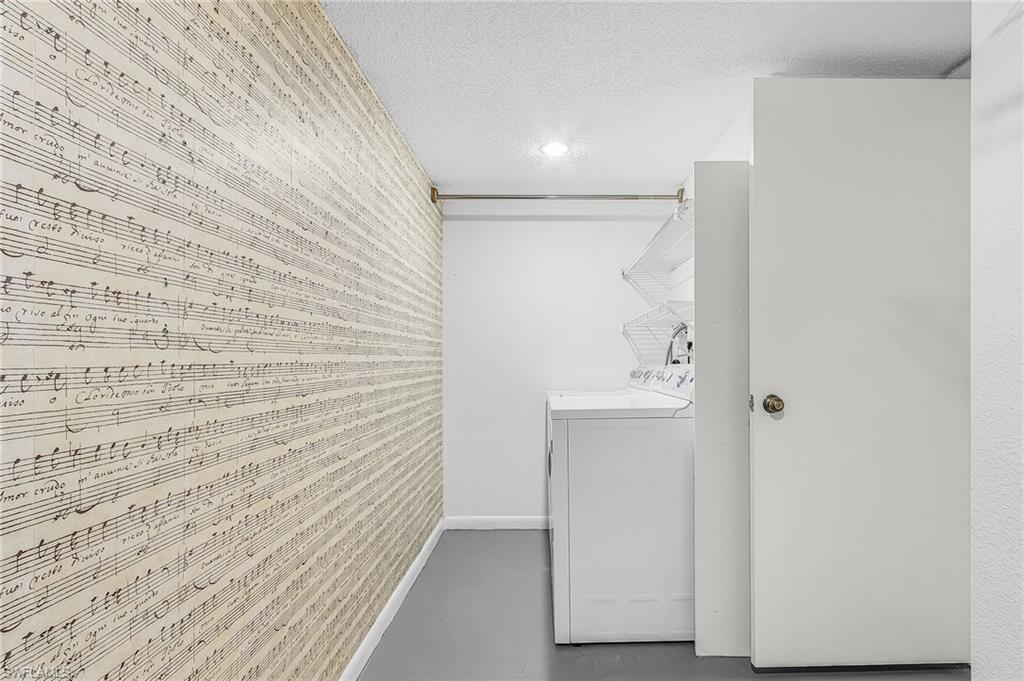 The spacious laundry room has a side by side washer & dryer w/hanging rack and extra storage space.