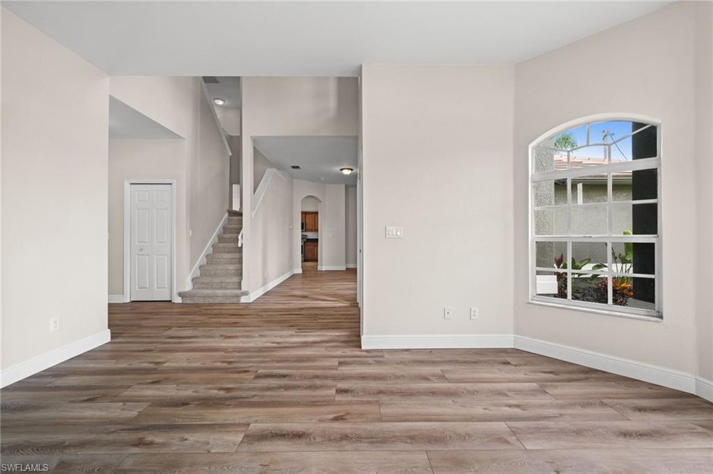 Open interior view highlights the flowing first-floor plan, wood-look flooring, staircase, and connection toward the kitchen and main gathering areas. The layout provides flexibility while maintaining an open, cohesive feel.