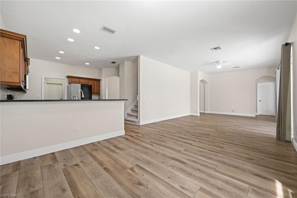 Wide interior perspective highlights the open living, dining, and kitchen layout with continuous wood-look flooring and generous floor space. This arrangement supports both everyday living and larger-scale entertaining.