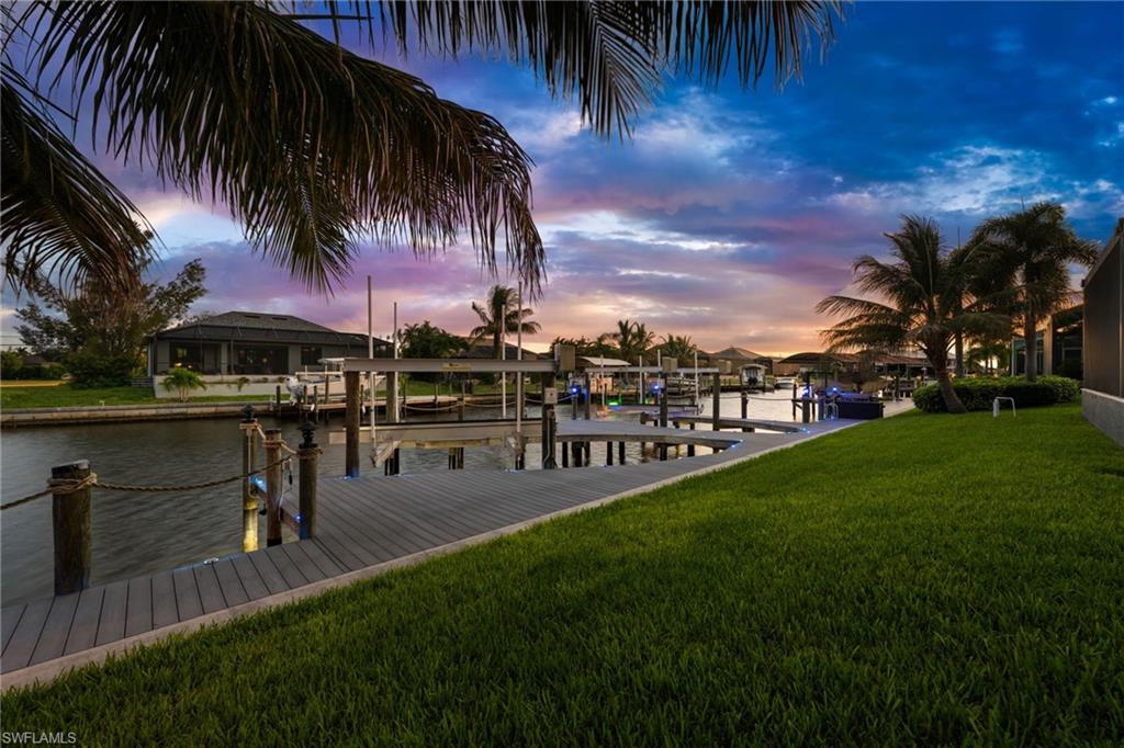 Canal-front setting with a custom dock, dual boat-lift setup, manicured lawn, and mature palms. Designed with boating in mind, the waterfront improvements include remote-controlled 10,000-lb. and 16,000-lb. boat lifts directly behind the residence.