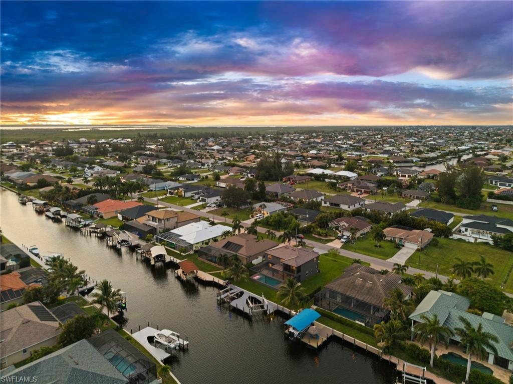 Aerial view highlights the home's location within an established Cape Coral canal neighborhood surrounded by waterfront residences, private docks, and navigable waterways. The perspective gives buyers valuable context for the property's boating-oriented setting.