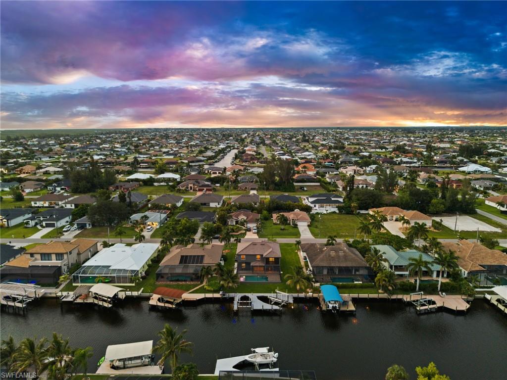 Elevated aerial perspective showcases the waterfront residence within a neighborhood of canal homes and private docks. This view helps illustrate the property's position within Cape Coral's extensive waterfront community.