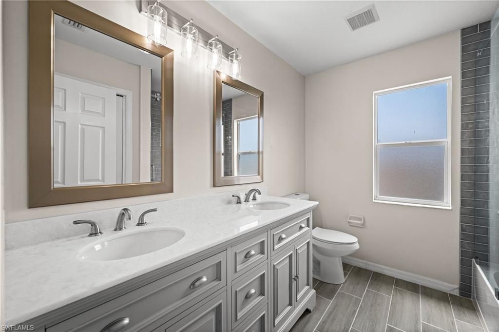 Remodeled upstairs bathroom includes a tiled tub and shower surround with glass enclosure and updated finishes. The property improvement records document a substantial bathroom remodel that included a new tub glass system.