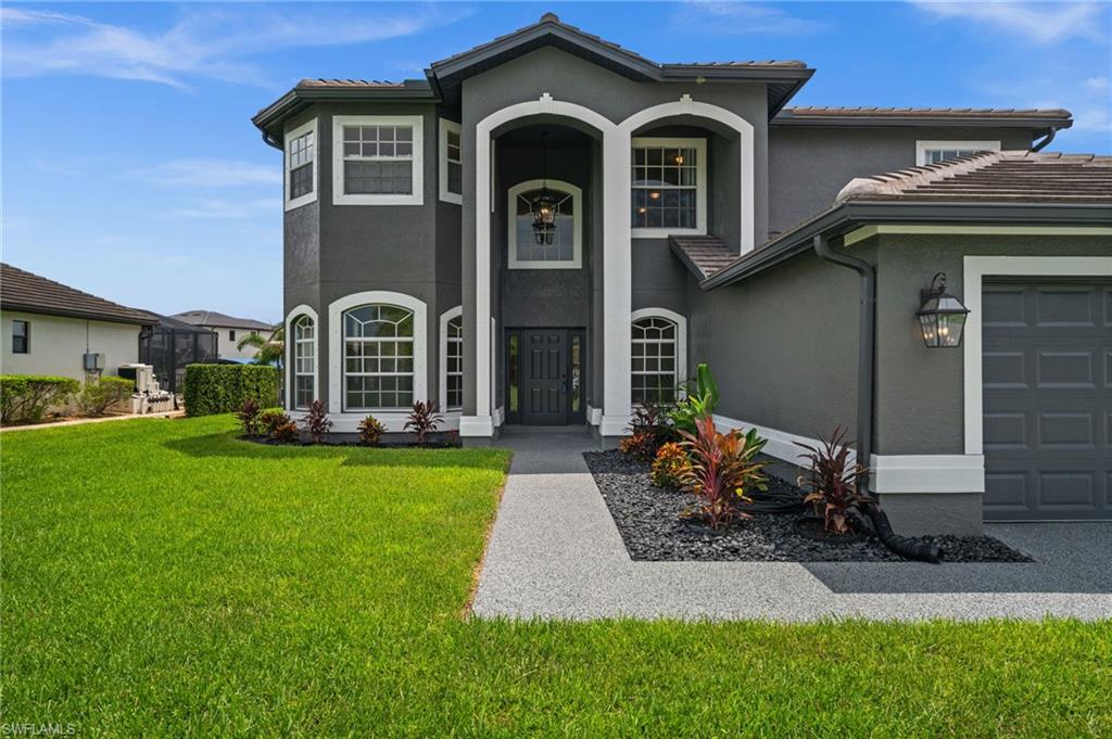 Grand covered entry features soaring columns, arched windows, landscaping, and a dramatic two-story façade. The architectural detail creates an impressive arrival while maintaining a clean, updated exterior appearance.