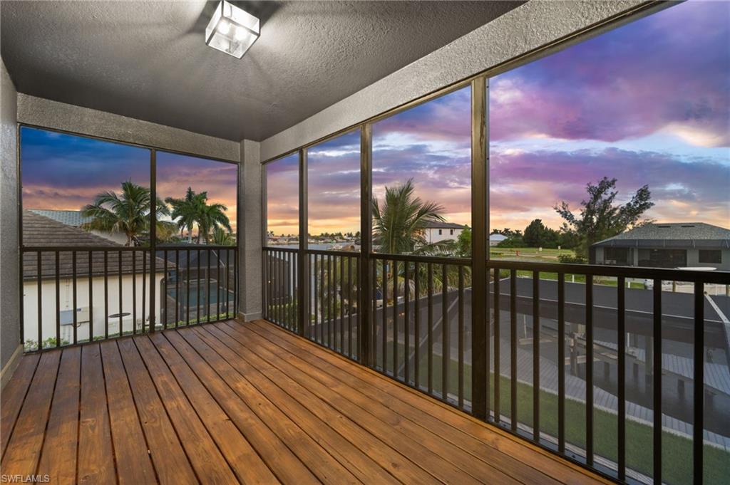 Private screened upper-level balcony overlooking the waterfront neighborhood, offering a peaceful outdoor retreat with palm-lined views and colorful Southwest Florida skies. This elevated outdoor space adds another place to relax while enjoying the canal-side setting.
