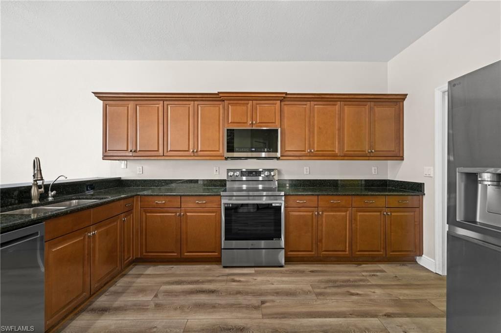 Well-appointed kitchen offers abundant wood cabinetry, black granite countertops, stainless appliances, and a functional U-shaped layout. The documented LG stainless appliance suite was selected to complement the existing dark granite surfaces.