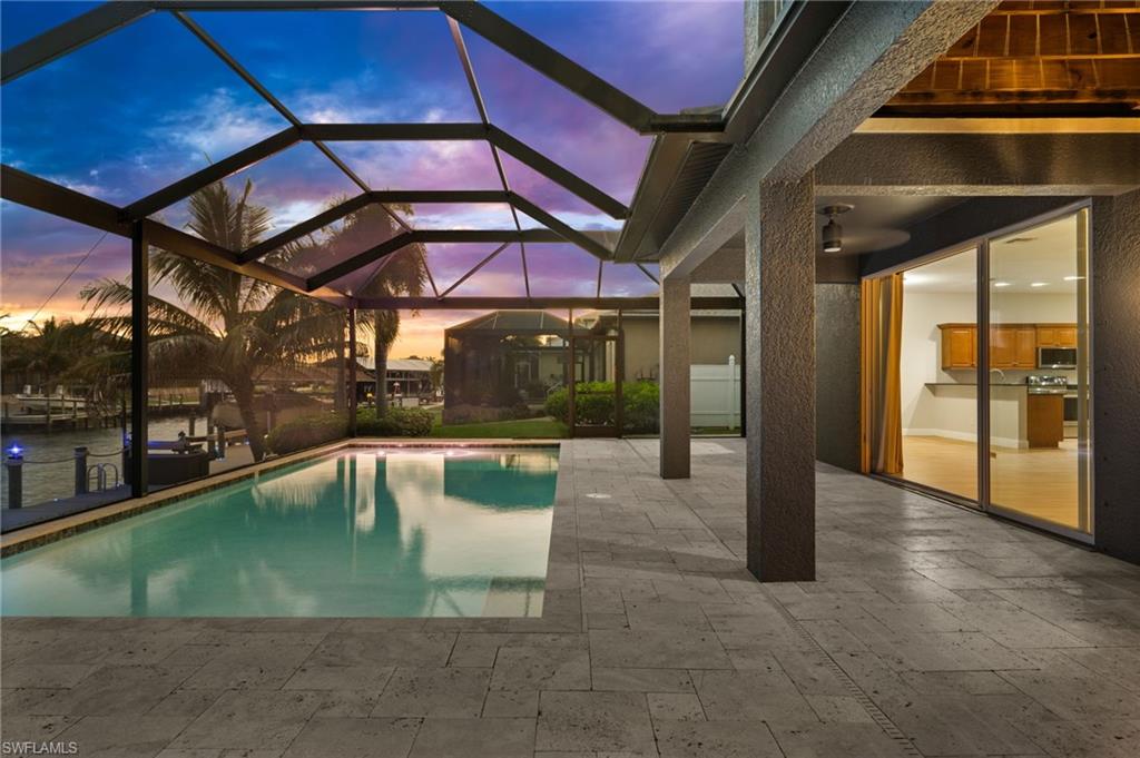 Sliding glass doors connect the interior living area directly to the screened pool and waterfront lanai, creating an easy flow for entertaining. The pool, spacious deck, canal setting, and tropical views showcase the indoor-outdoor lifestyle associated with Cape Coral waterfront living.